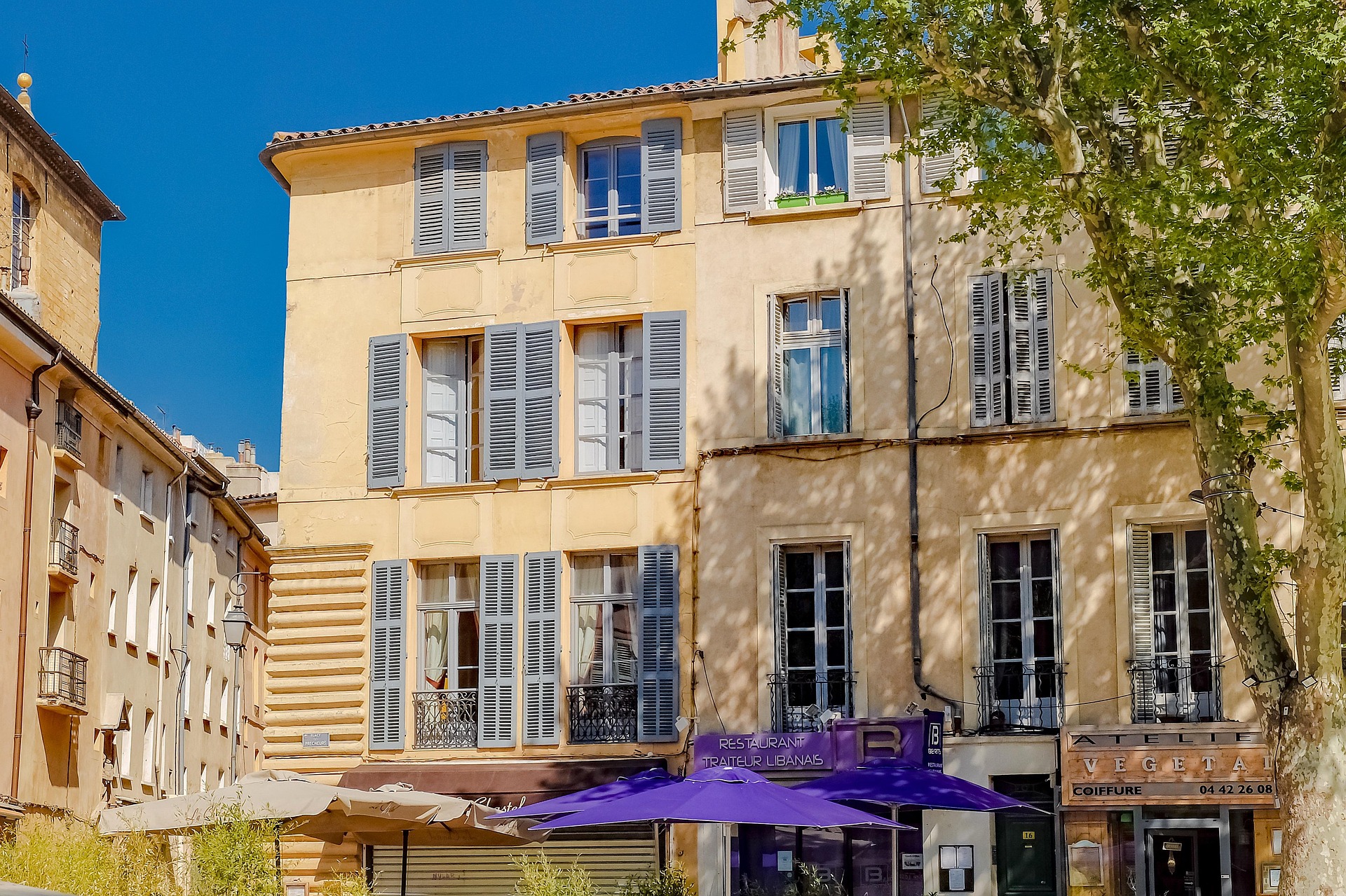 Façade d’immeuble provençal avec volets gris en centre-ville, idéal pour une chambre d’hôtes en Provence